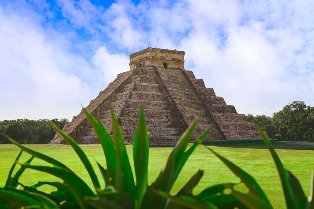 Piramida Kukulkana w Chichén Itzá na Jukatanie w Meksyku, widziana zza zielonych liści.