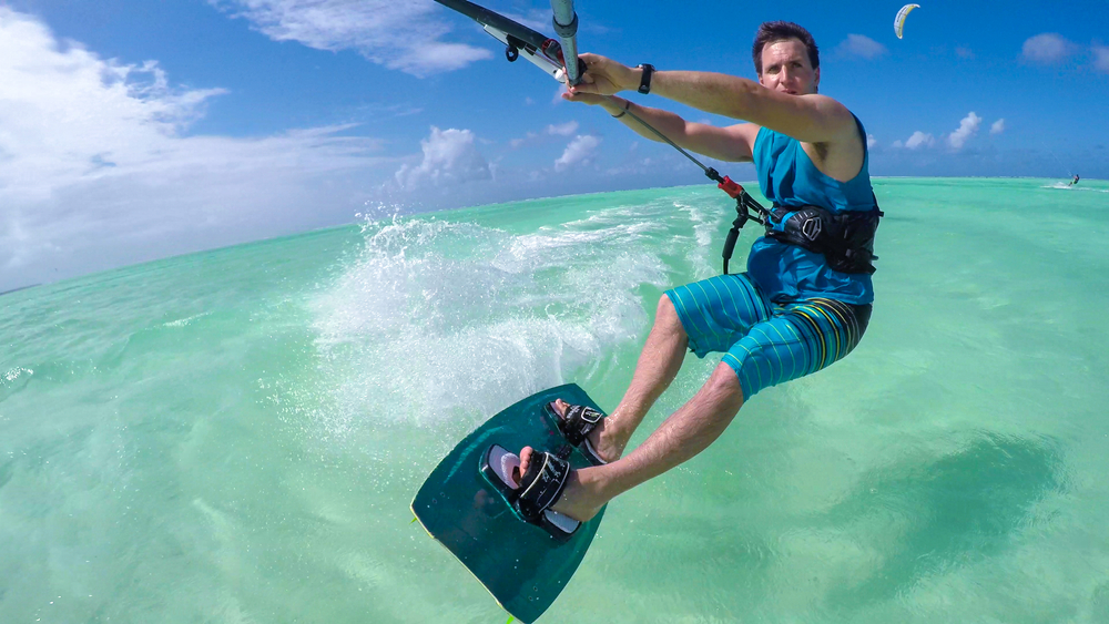 Kitesurfer na desce płynący po turkusowej wodzie u wybrzeży Zanzibaru.
