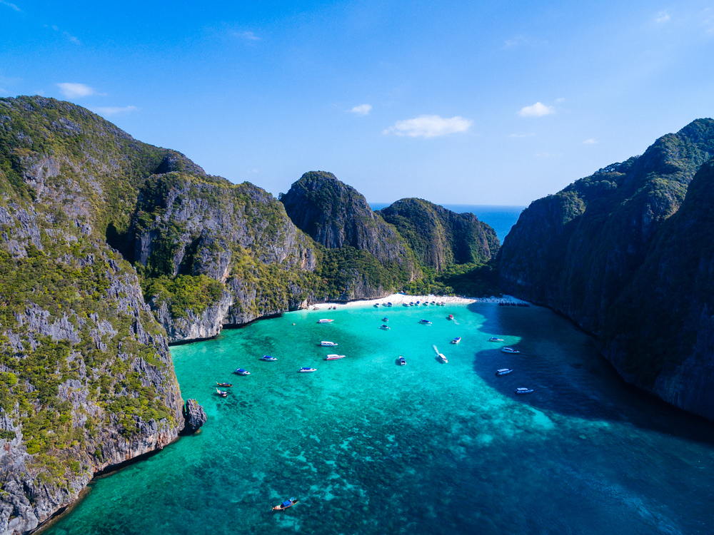 Widok z góry na turkusową zatokę Maya Bay, plażę i wysokie wapienne skały na wyspach Phi Phi w Tajlandii.