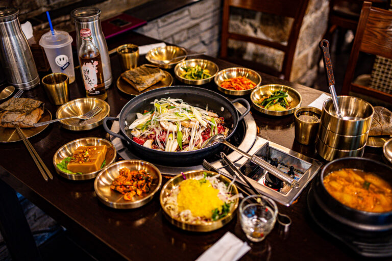 Koreański grill na środku stołu i małe miseczki z dodatkami do wspólnego posiłku.