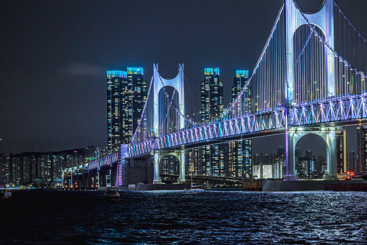Rozświetlony most Gwangan nad zatoką w Busan nocą.